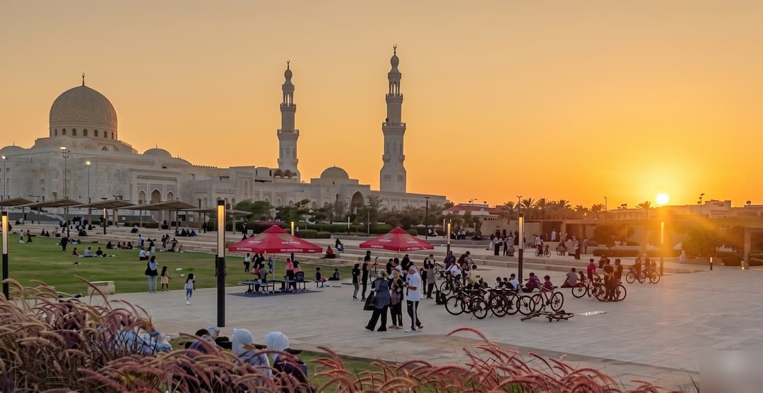 Grand mosque at sunset with families gathering on the plaza